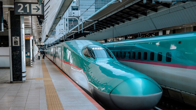 ホームに停車中の新幹線の先頭部分。奥の線路にも同じカラーリングの新幹線。