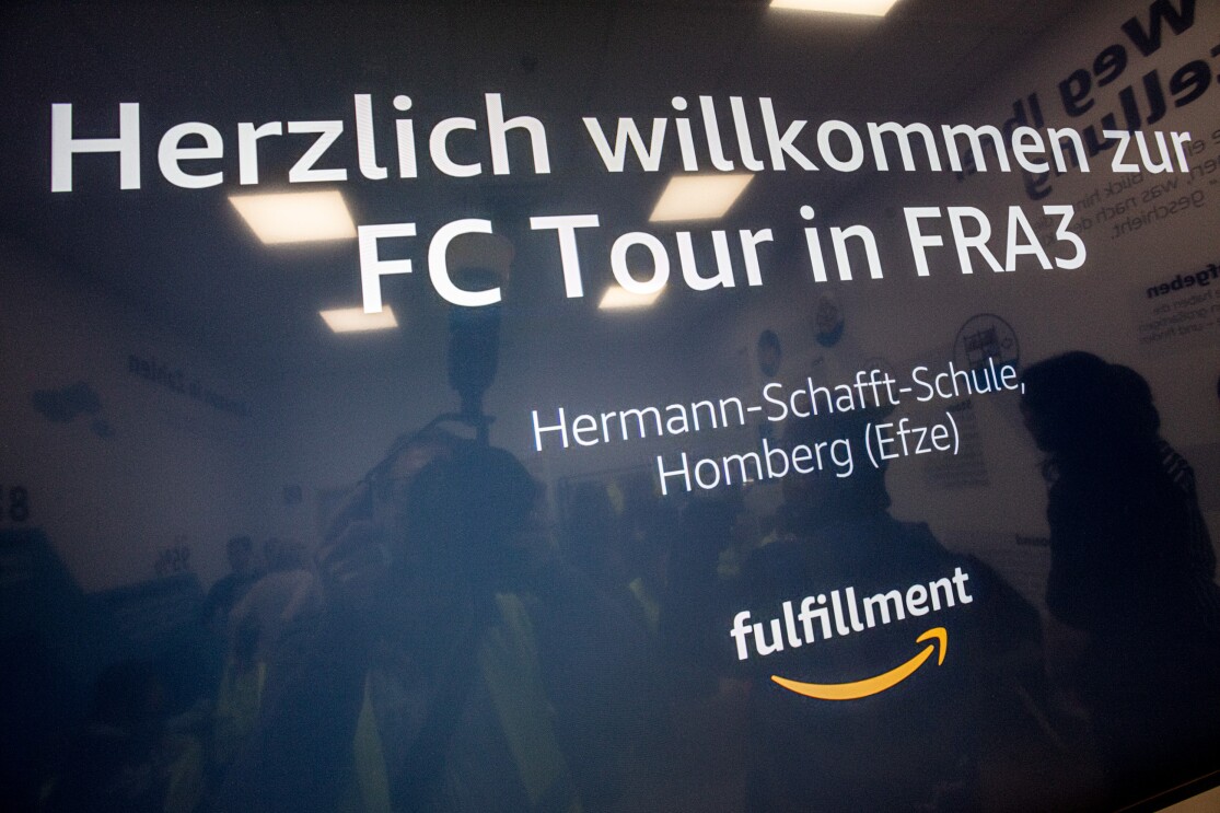 Ein Willkommensschild für die BesucherInnen mit weißer Schrift auf blauem Hintergrund.