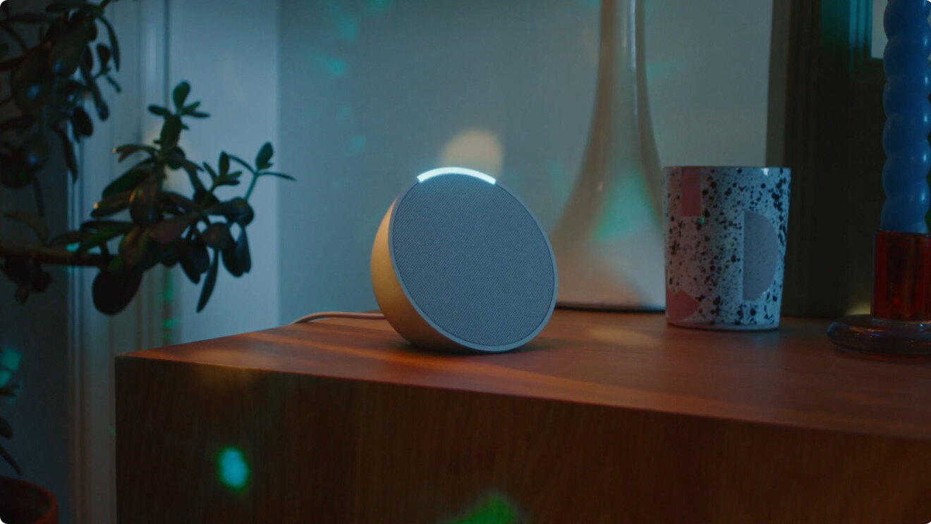 Dispositivo Echo Pop sobre un mueble de color marrón. 