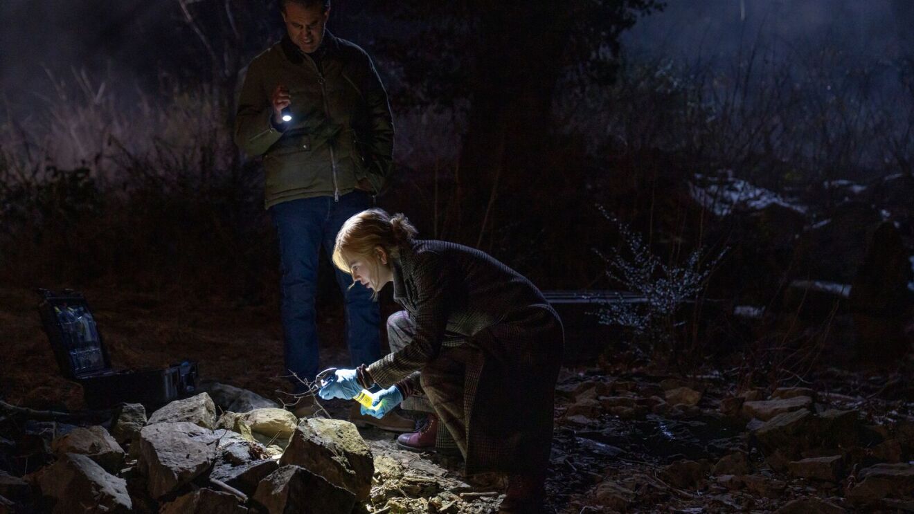 Investigators examine rocky terrain at night with flashlights