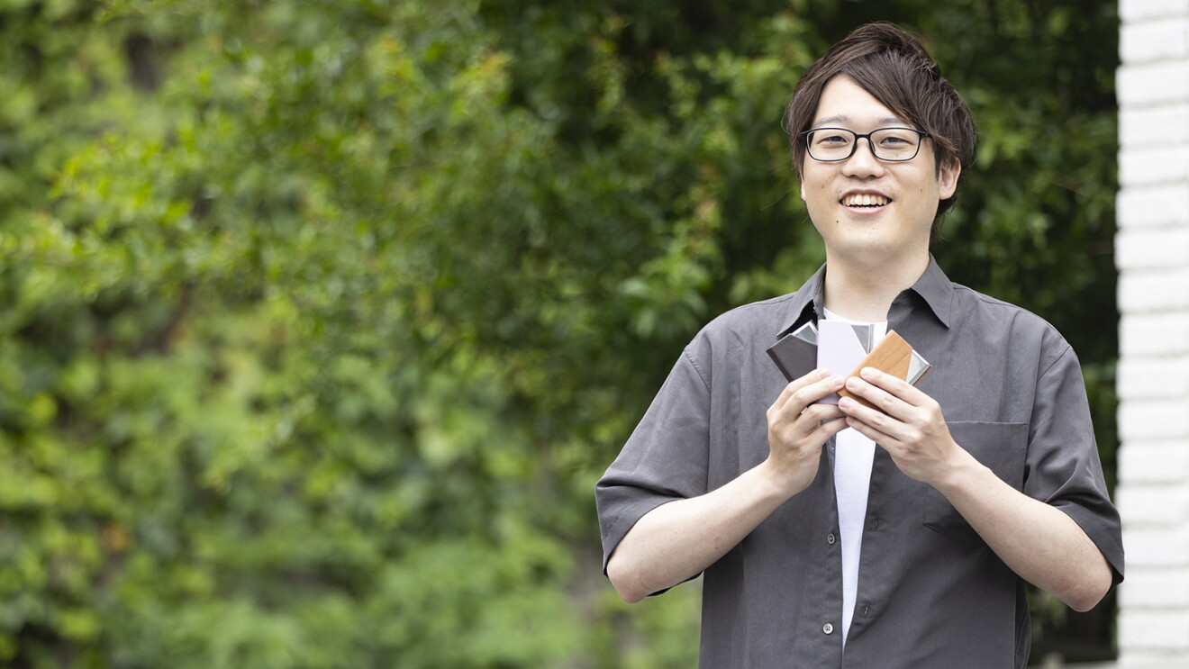 メガネをした男性が名刺入れを3つ手に持っている