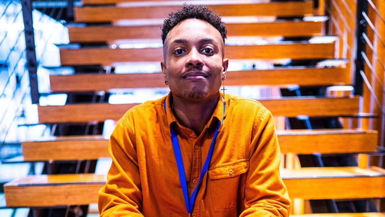 An image of a man smiling for a photo sitting on steps in an Amazon office.