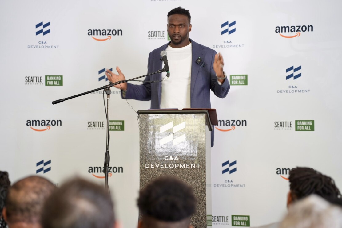 Cliff Avril stands behind a podium speaking to an audience of community advocates and business leaders