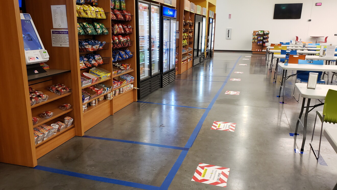 Zobacz wnętrze pokoju amatorskiego w centrum realizacji Amazon. Linie są przyklejone na podłodze, aby zilustrować miejsce, w którym powinni stać współpracownicy, aby zachować dystans społeczny wobec osoby przed nimi.