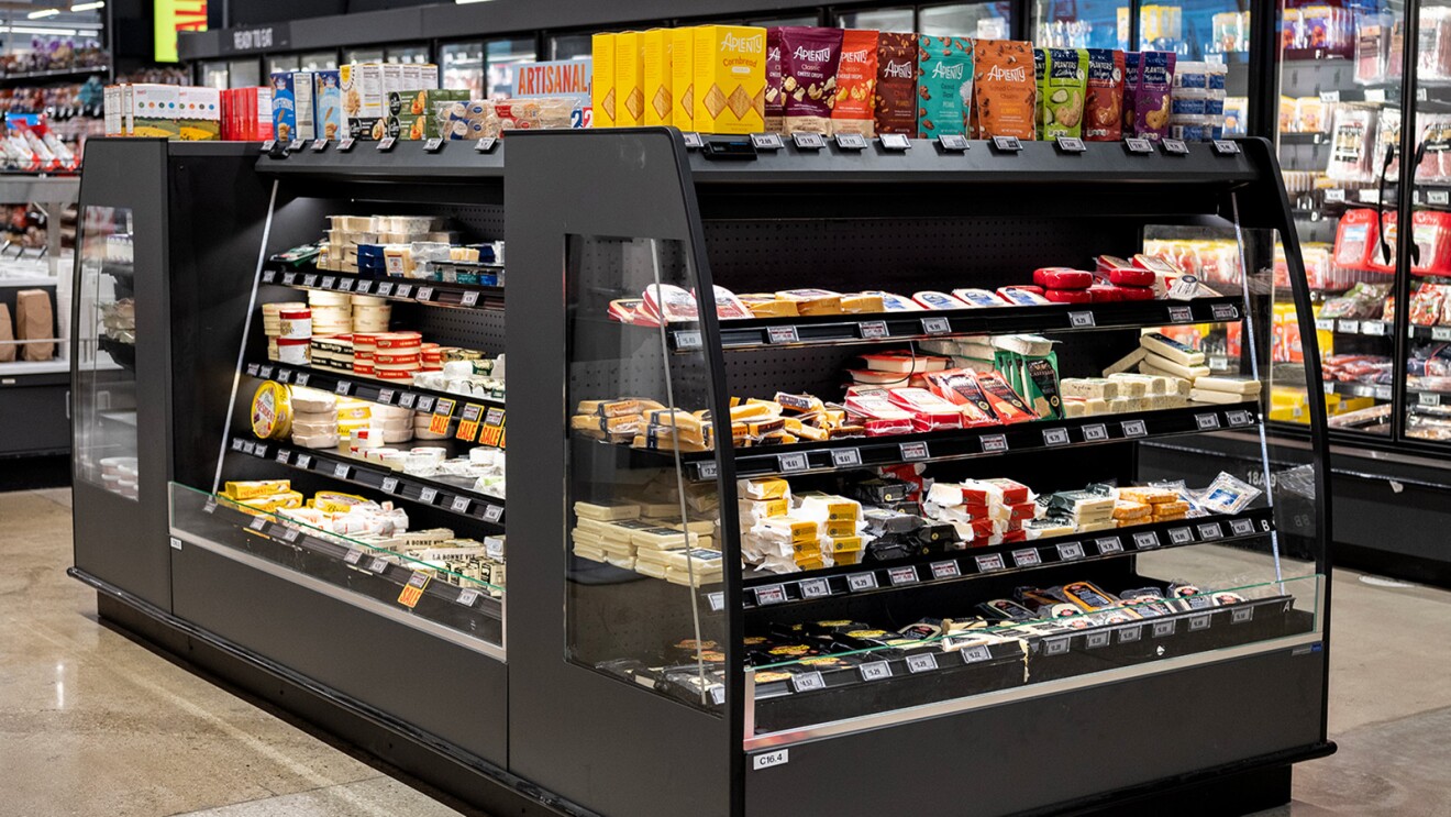 A photo of different cheeses on display in a case inside an Amazon Fresh store.