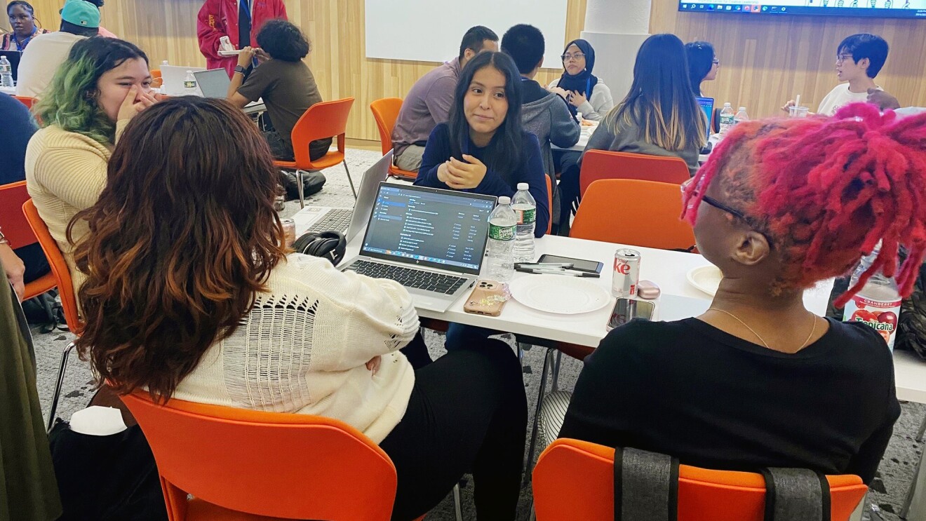 An image of a group of apprentices sitting on a table and talking to each other.