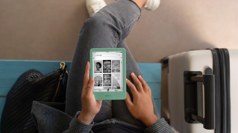 Person reading a Kindle on green Kobo device while traveling