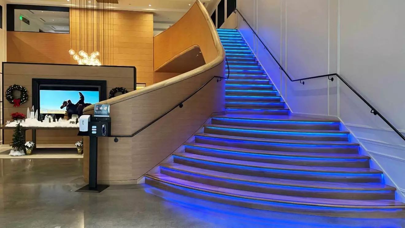 右側には青く光っている大きな階段があり、その階段の後ろには大きなテレビが壁に取り付けられている