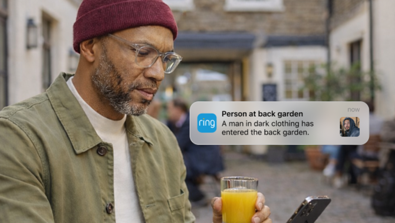 Man wearing hat and glasses is notified by Ring from his phone. 
