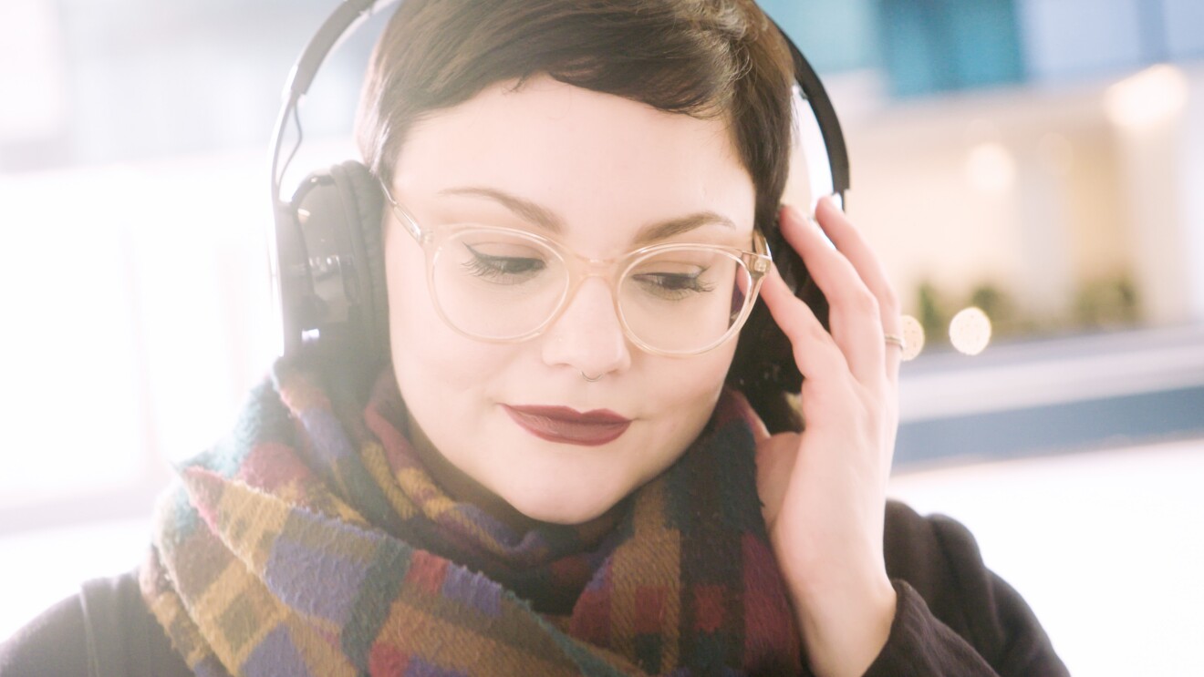 Ritratto di Giulia Massari, Marketing Manager Audible, mentre indossa delle cuffie e ascolta della musica.