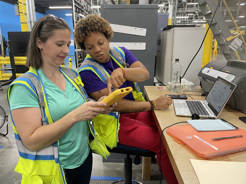 Catherine Lemonds holds a tablet while her colleague points to the tablet and talks with Catherine.