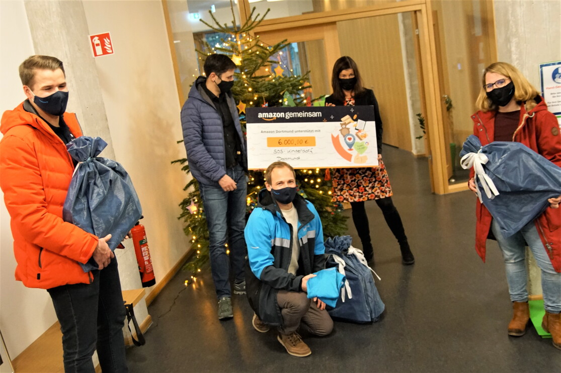 Verschiedene Personen vor einem Weihnachtsbaum mit spendenscheck