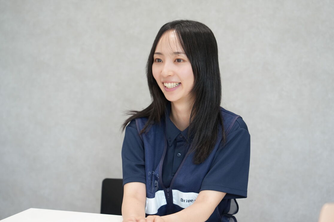 紺色のシャツと安全ベストを着ている女性が座りながら話している