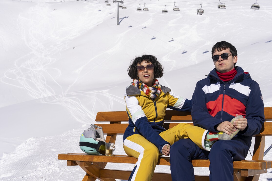 Asa Butterfield and Cora Kirk sit on a ski slope