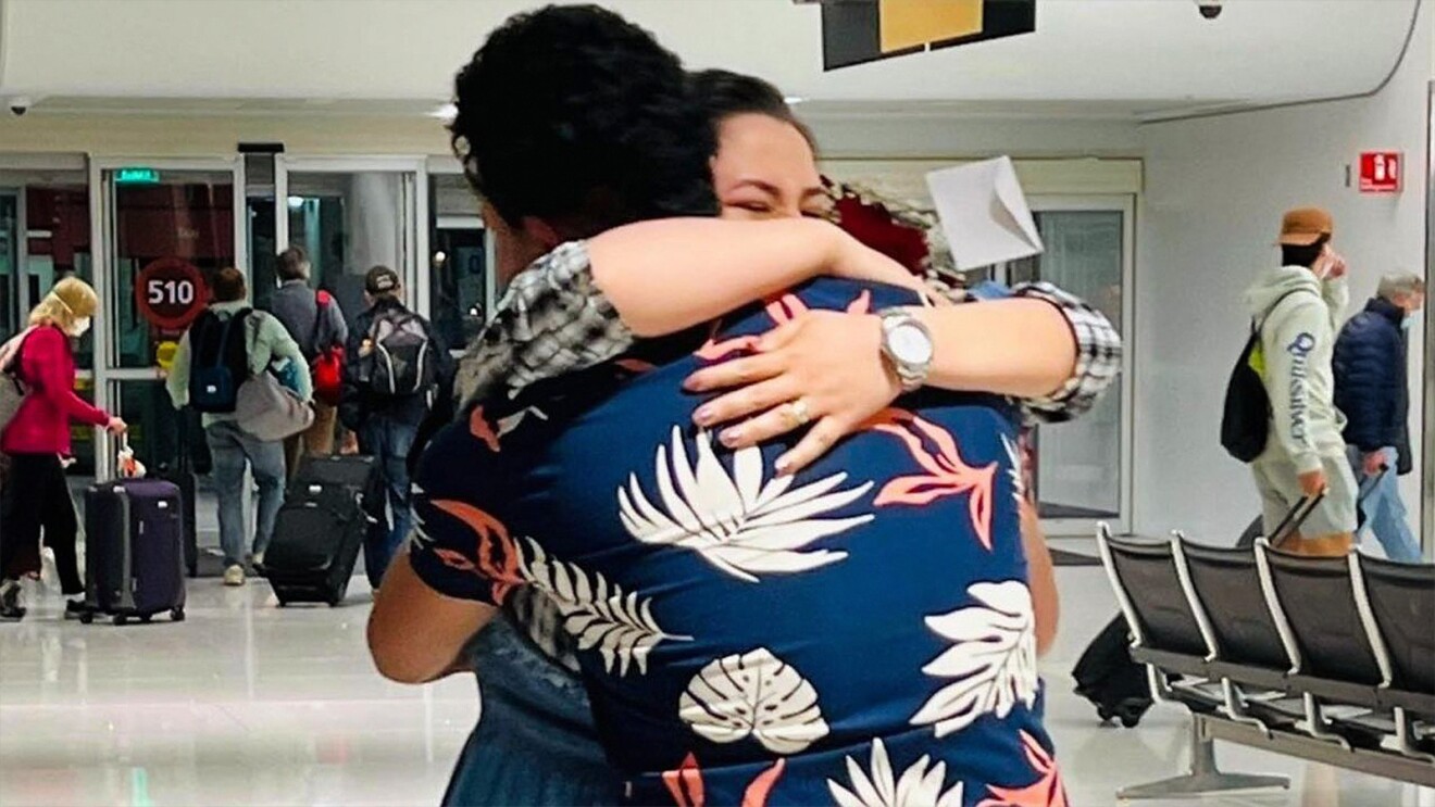 A photo of a former Afghan interpreter hugging their spouse in an airport.