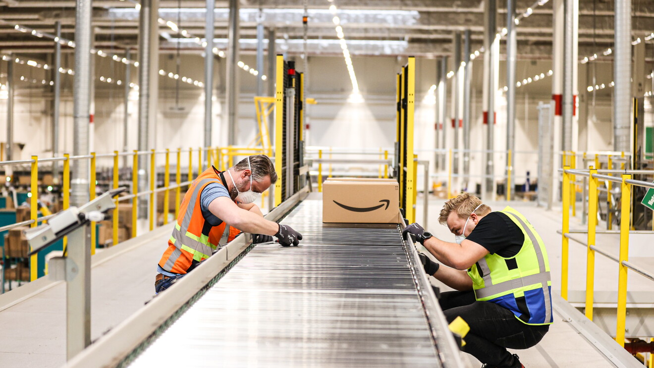 Two engineers assembling a track with Amazon package in background.
