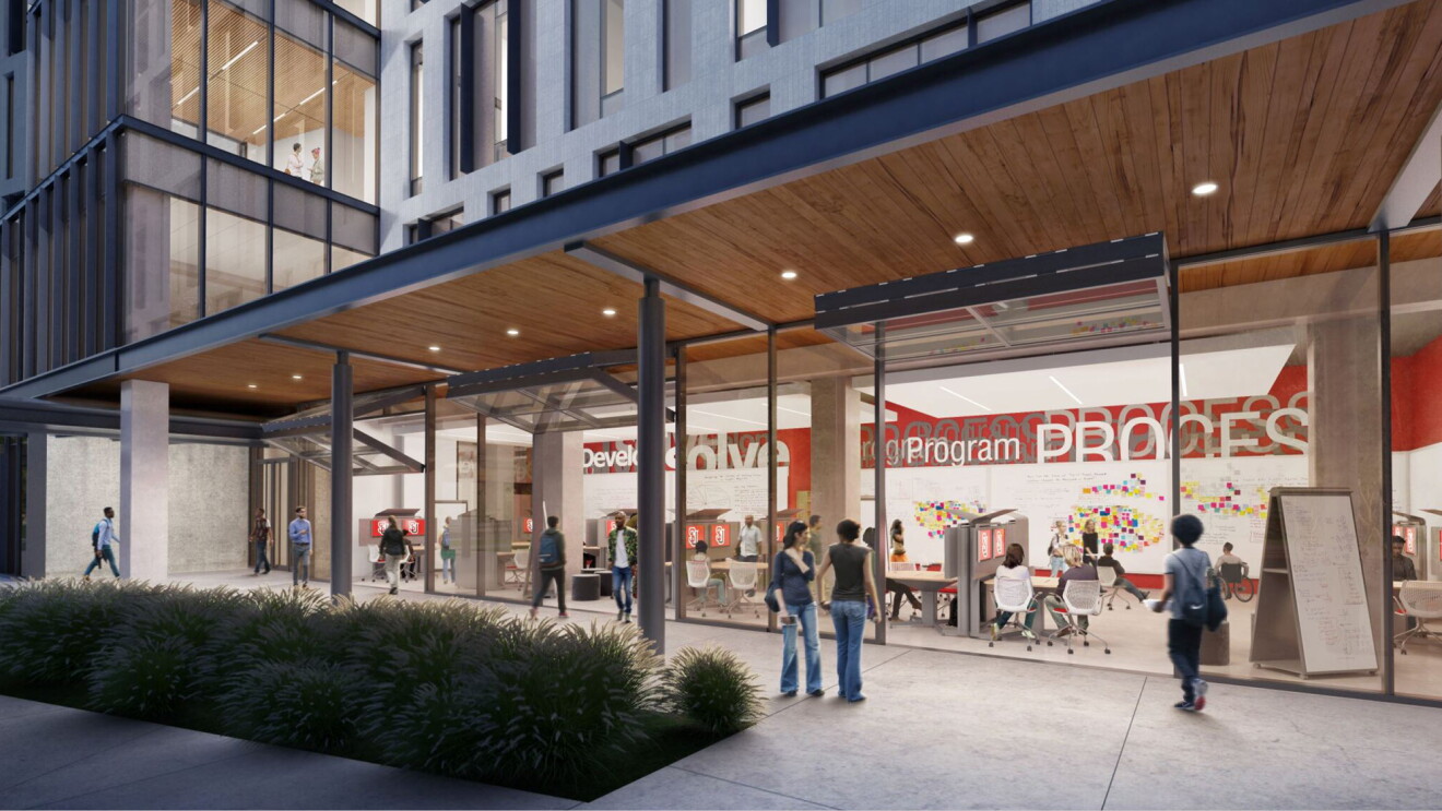 A rendering of the future Seattle University  Center for Science and Innovation, shows a wall of windows, with students working on computers inside the space. The exterior shows individuals walking by the urban building, and a section of landscaped grasses.
