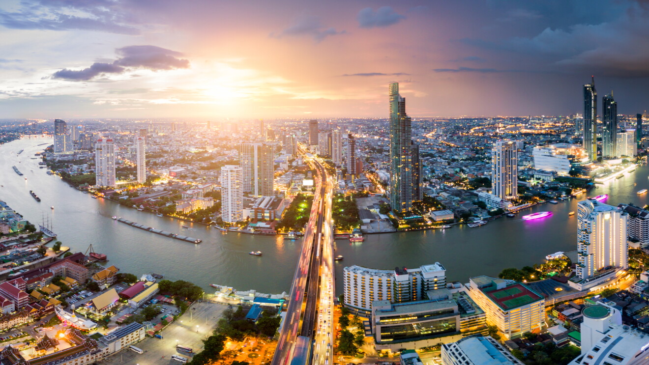 Aerial view of Bangkok skyline and skyscraper with light trails on Sathorn Road center of business in Bangkok downtown. Panorama of Taksin Bridge over Chao Phraya River Bangkok Thailand at sunset.