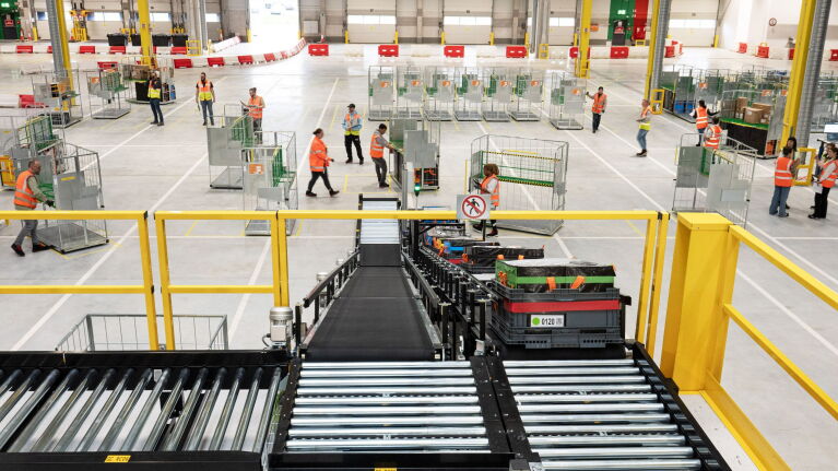 Amazon Logistikzentrum mit Mitarbeitenden und automatischen Sortieranlagen.