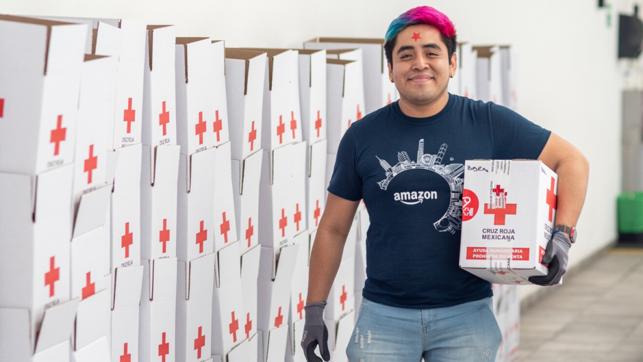 Voluntaria de Amazon delante de las cajas de Cruz Roja que han preparado para donar.
