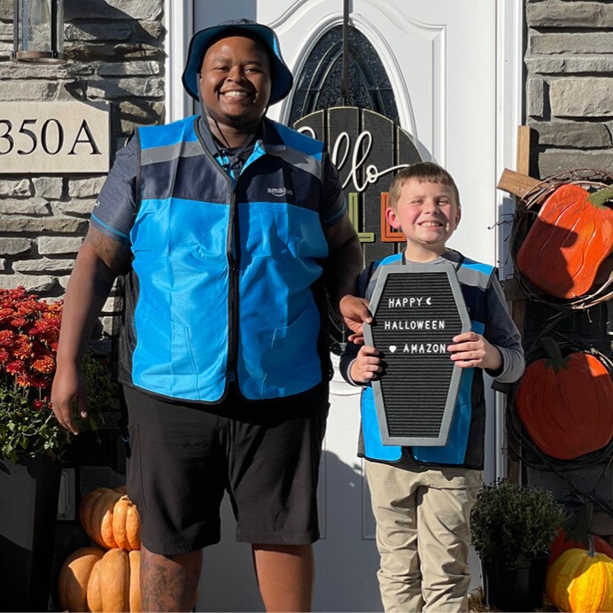 Landon wears an Amazon delivery driver costume and smiles as he poses for a picture outside his home.