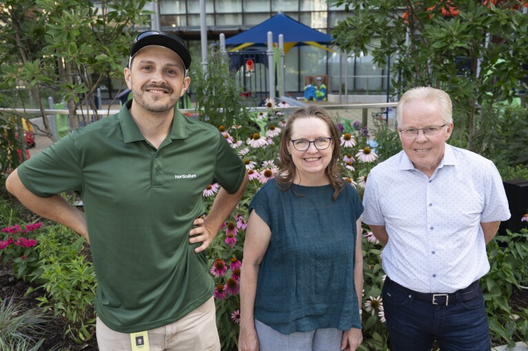 Three horticulturists standing side by side in front of the Met Park’s Butterfly Garden