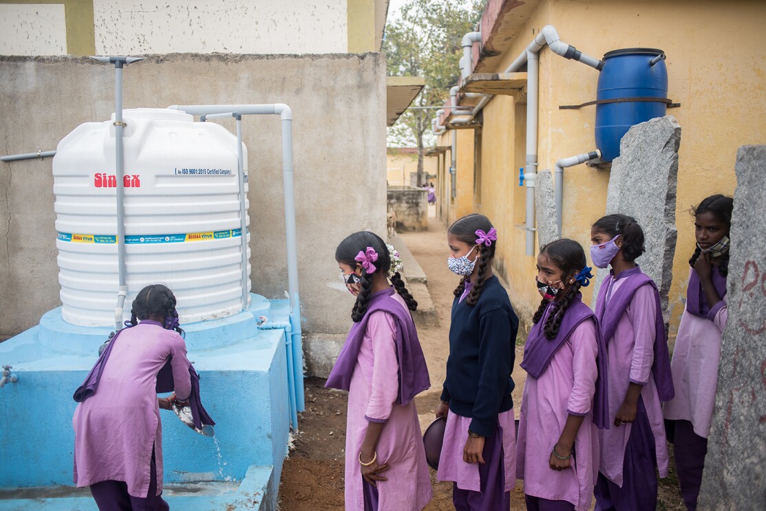 School students washing their hands and plates with soap and clean water at the water storage tank with a capacity of 2500 liters connected to a Rain Water Harvesting (RWH) constructed by WaterAid India inside the complex of Zilla Parishid High School.