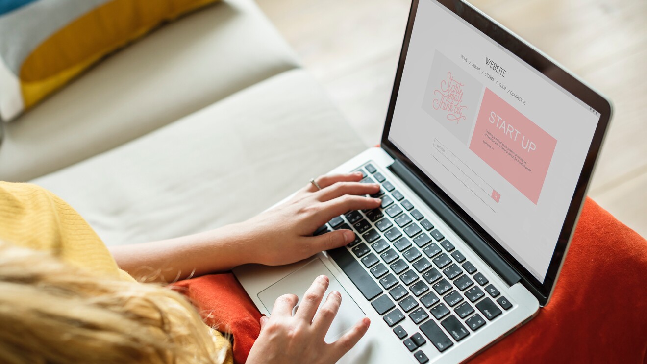 Woman working on a laptop computer, her hands are posed over the keyboard of the device.