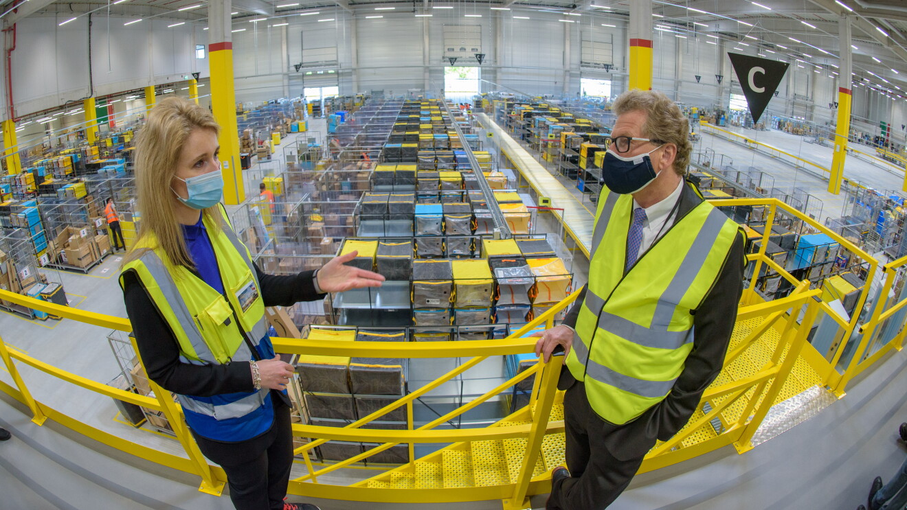 Der Minister steht rechts zu einer Amazon Managerin
