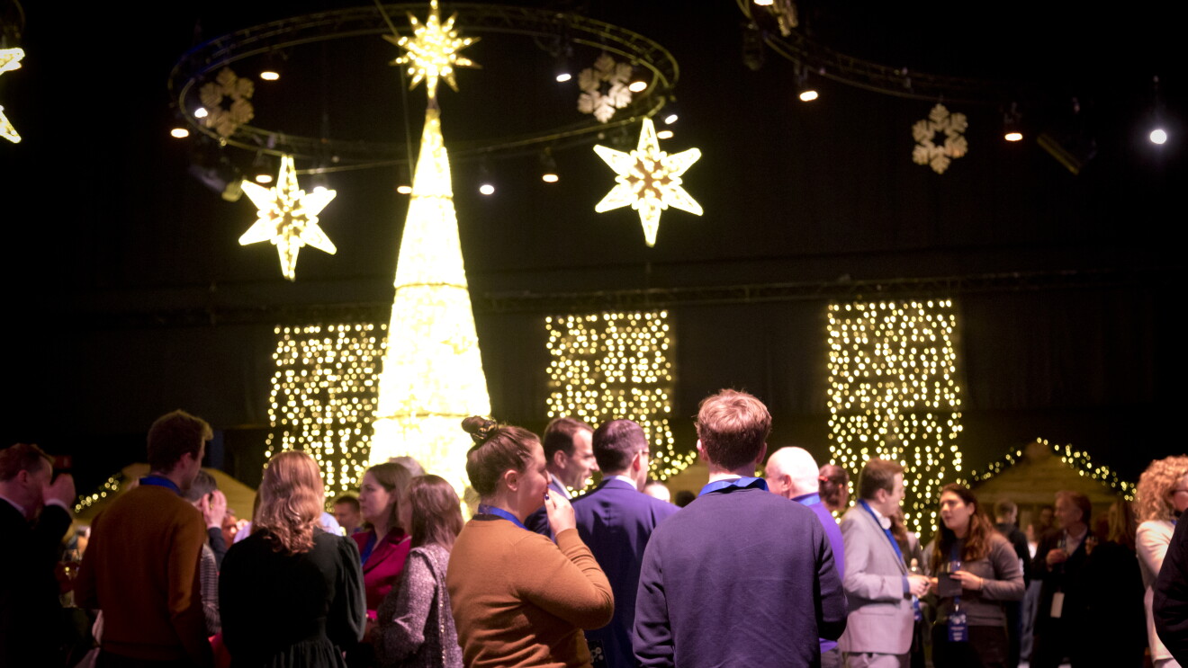 Christmas market attendees standing under ornamental Christmas lights