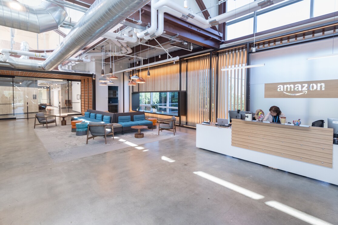 Entrance to the Amazon San Diego building. A reception desk is in the foreground, behind it are multiple seating options and an entrance to the work areas.