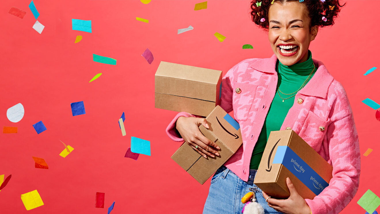 Imagen de promoción de Prime Day con una mujer sonriendo entre confetí y agarrando tres cajas de Amazon Prime Day. 