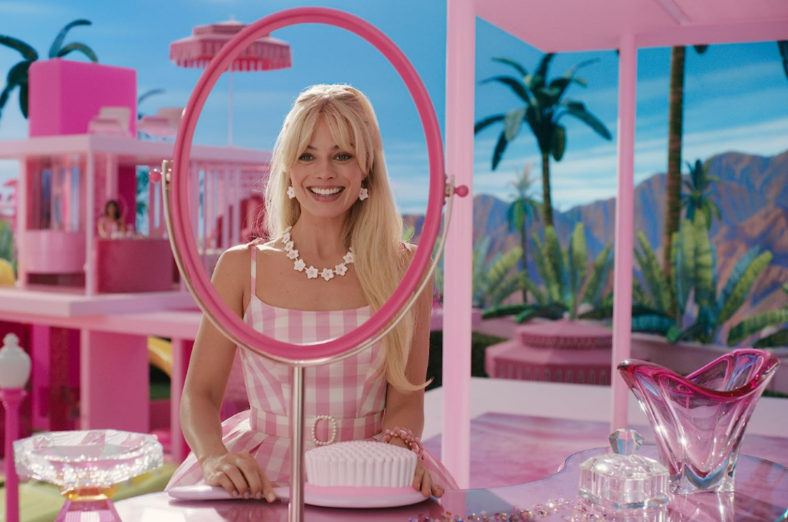 A blonde woman wearing pink smiling into a mirror