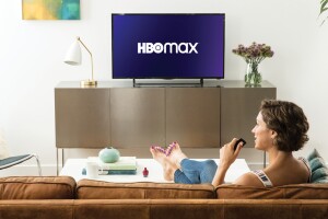 Someone sitting on the couch watching a TV displaying the HBO Max logo.