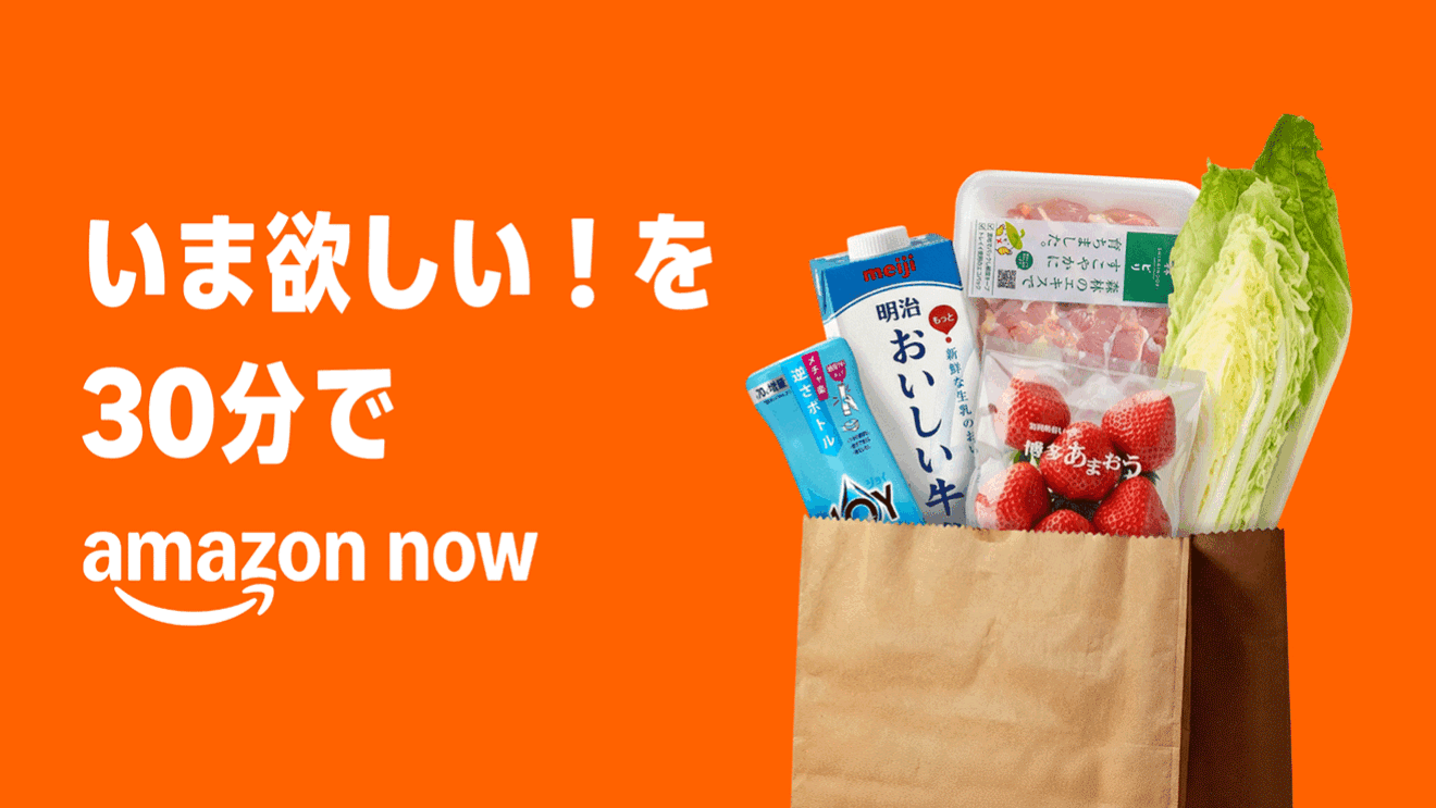 濃いオレンジ色の背景に白で大きく「いま欲しい！を30分で」の文字。その下に「amazon now」とアマゾンのロゴ。文字の右側に、紙の買い物袋に入った白菜、苺、牛乳などの写真。