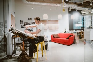 An artist works at a desk in an art studio.