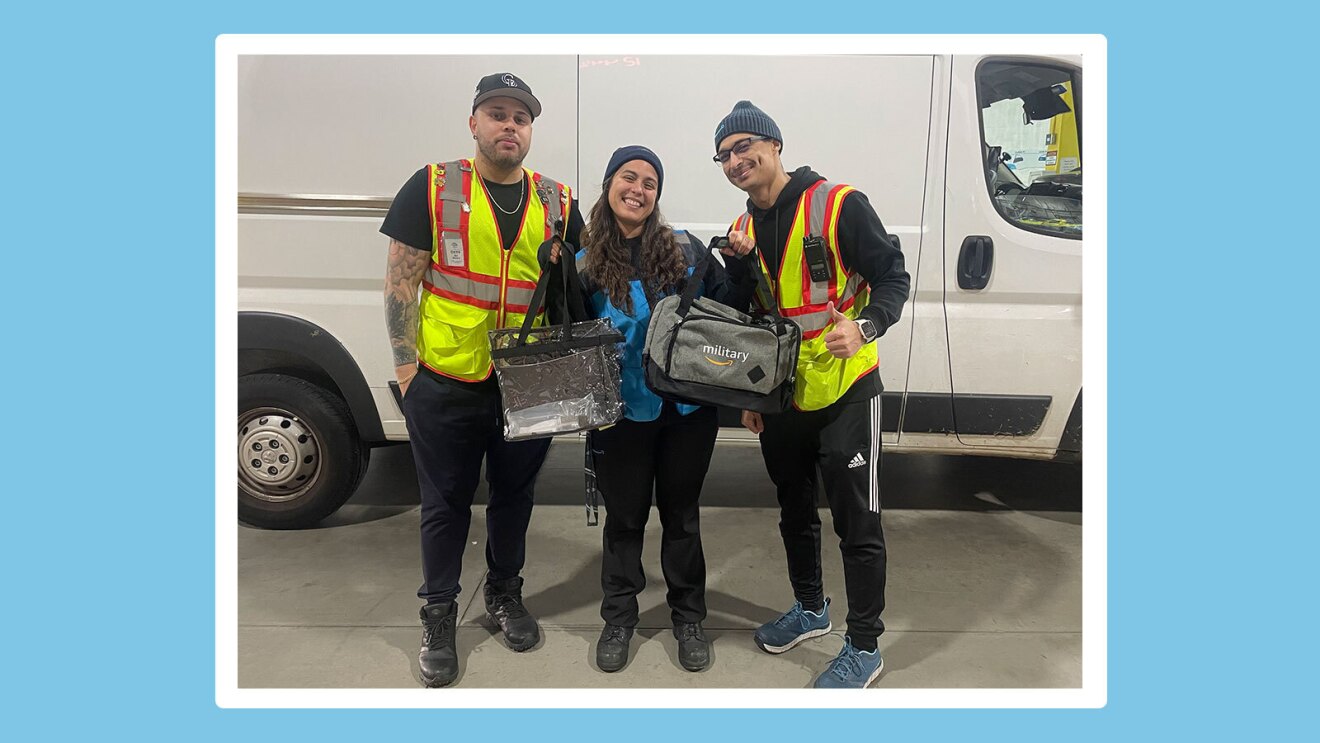 Brianna smiles and stands in between two colleagues and holds up two bags in front of a delivery vehicle.