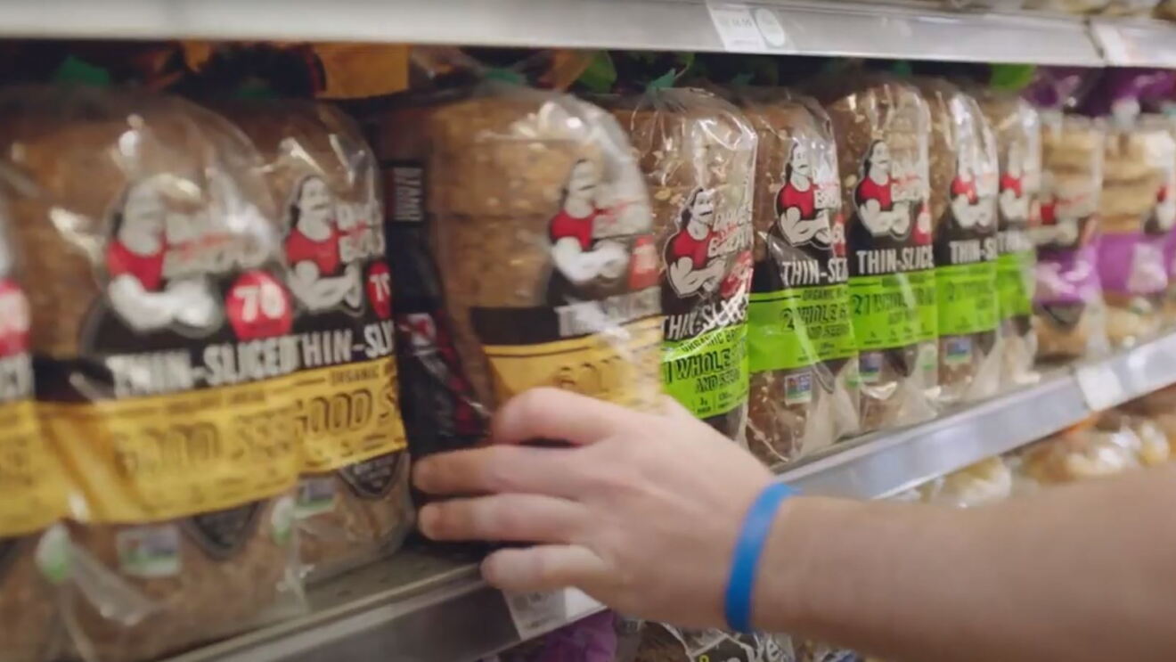A person removes a package of bread from a shelf at a Whole Foods Market store. 