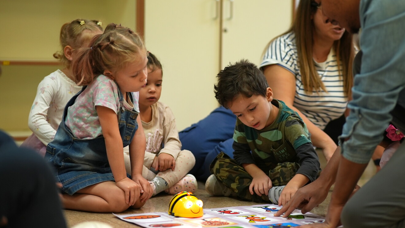 Alumnos de primaria con un robot de lego en el suelo. 