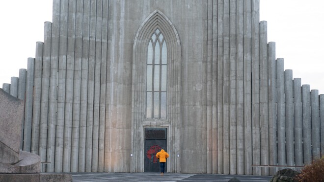 一个穿着黄色外套的人站在灰色高墙上的两扇门前。