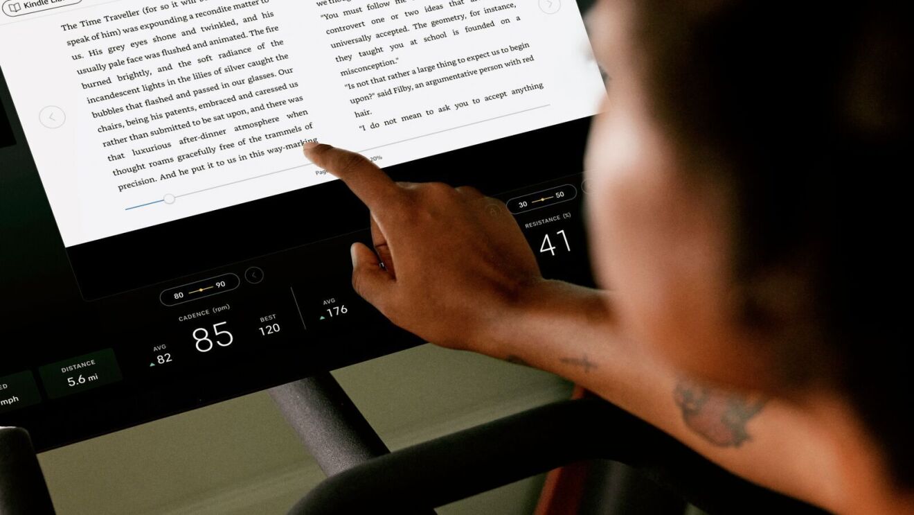Peloton x Kindle: woman on a Peloton reading the Kindle while working out