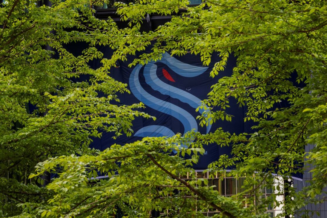 Seattle Kraken flag hanging from a building in downtown Seattle, surrounded by trees