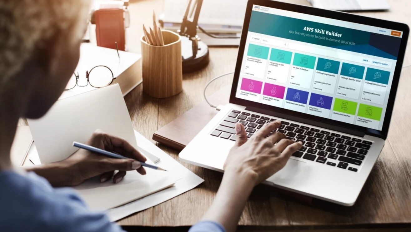Woman holds pencil while she navigates the AWS skills builder website on her laptop