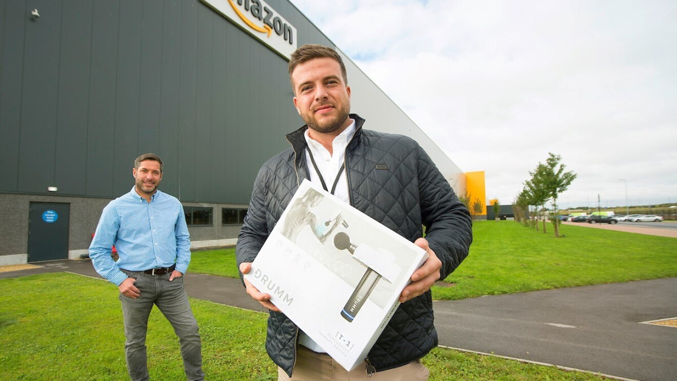 Business owner stood in front of Amazon fulfilment centre holding product in a box 