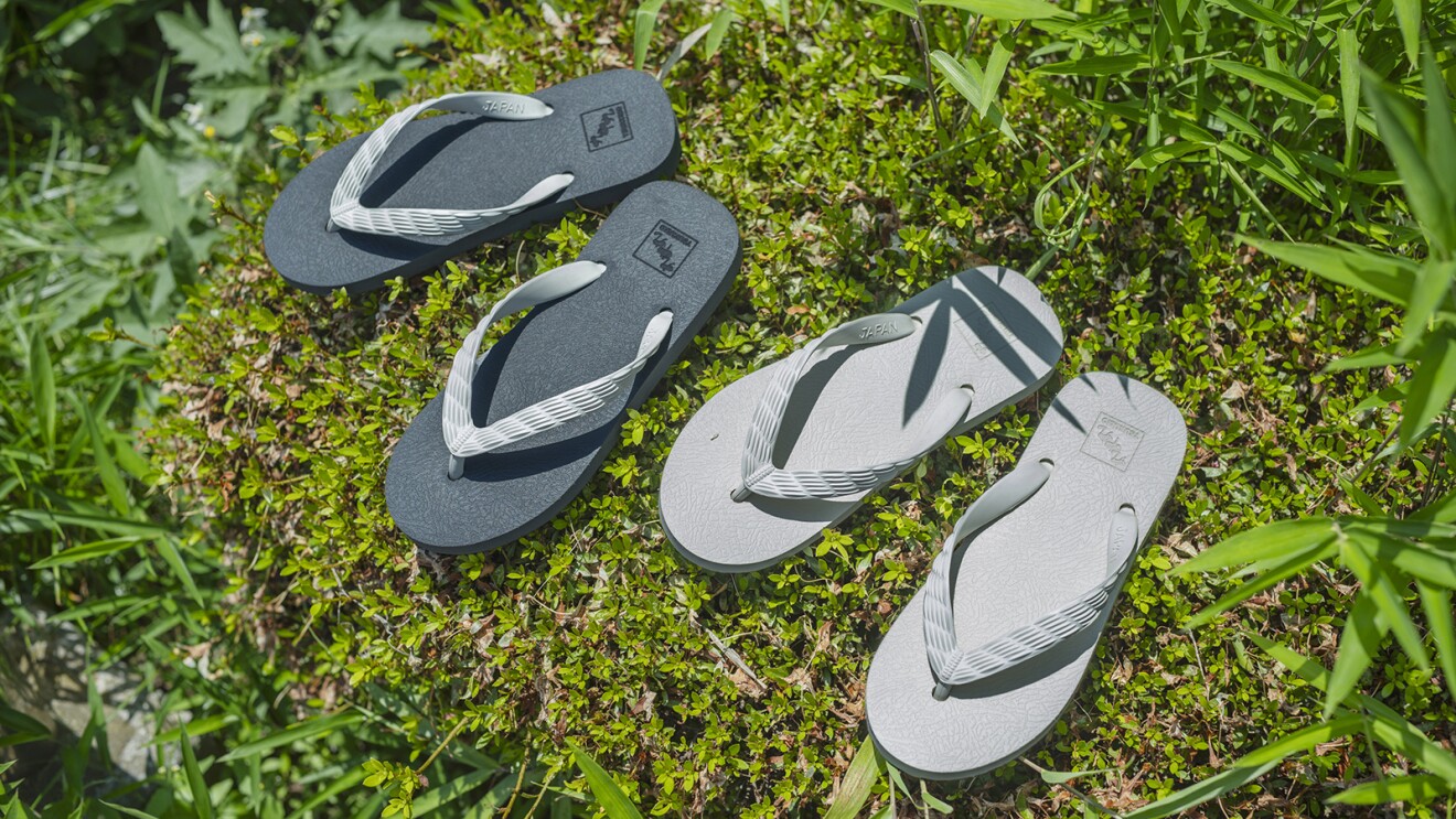 草の上に置かれた2足のビーチサンダル。黒とグレー