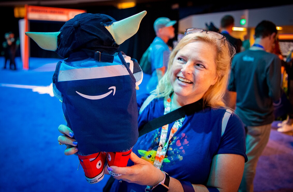 An image of a woman holding a Grogu doll dressed as an amazon employee