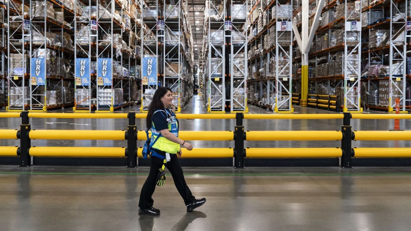 Amazon employee in safety vest walking through massive warehouse facility