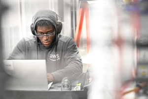 A photo of a data center technician working at a desk inside a data center on a laptop device.