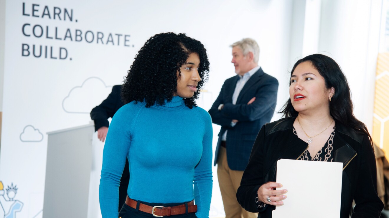 A photo of a student walking next to a speaker at an AWS event in New York.