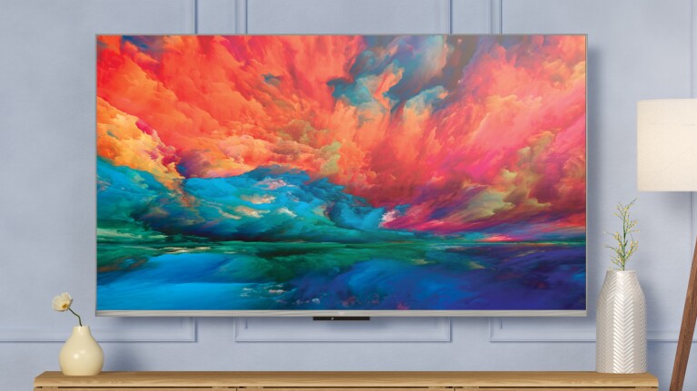 An image of a Fire TV mounted on a wall with the screen showing a painting of faded colors. 